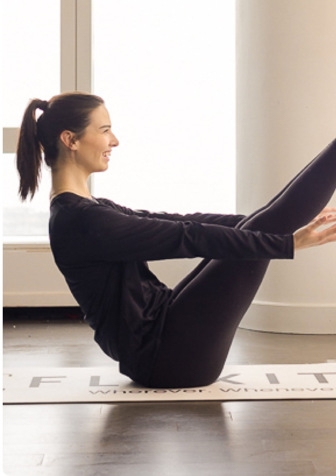 Woman performing teaser pilates pose, seated with chest and legs held up